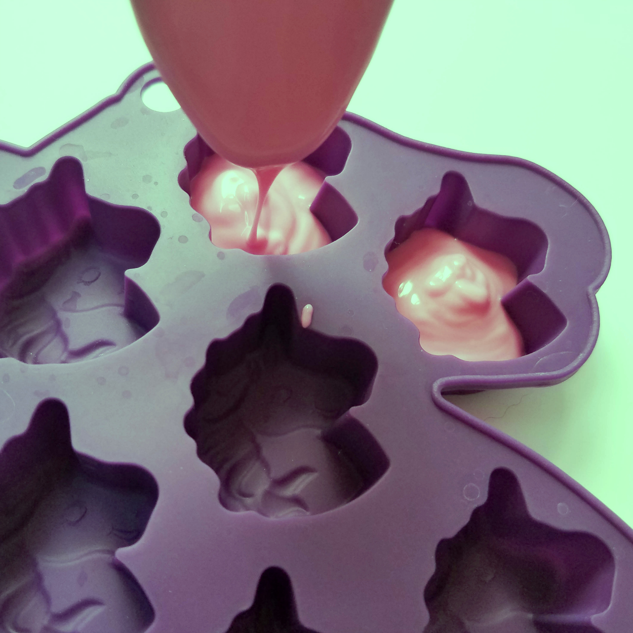 filling silicone candy mold with pink melted candy