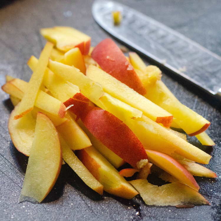 peach slices and knife on cutting board