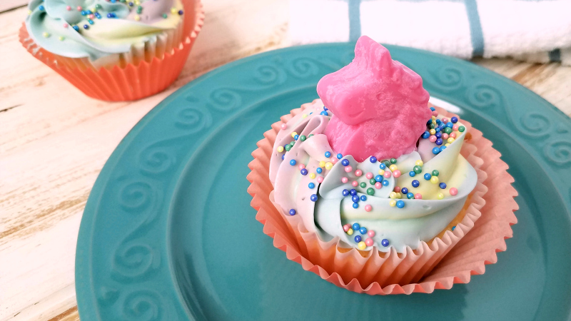 pink unicorn candy cupcake on teal plate