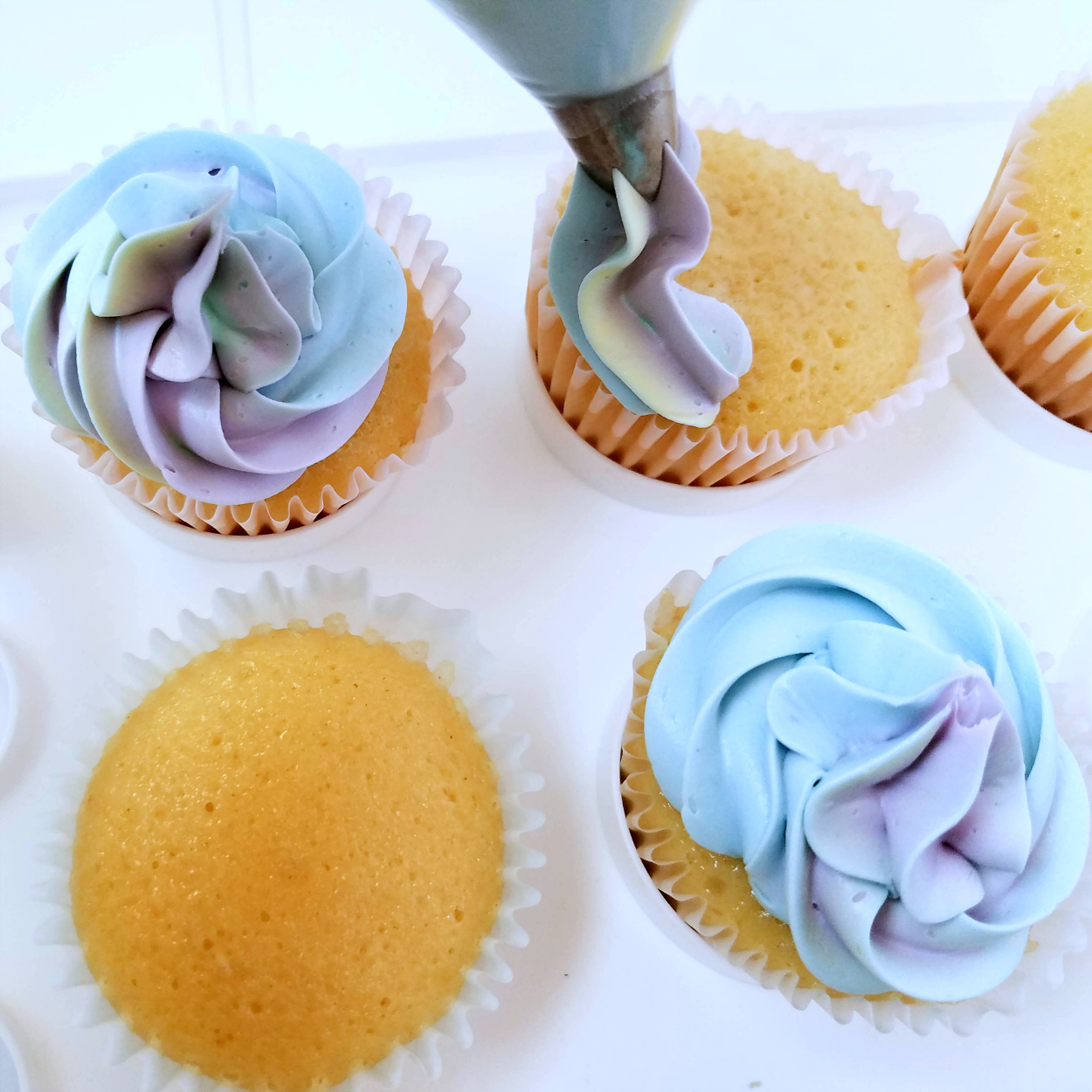 piping unicorn frosting onto cupcakes