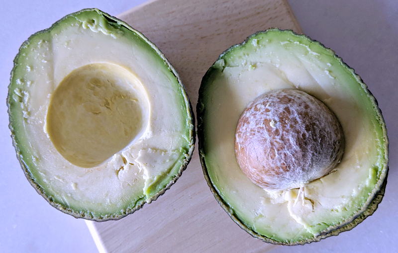 avocado sliced in half on small cutting board