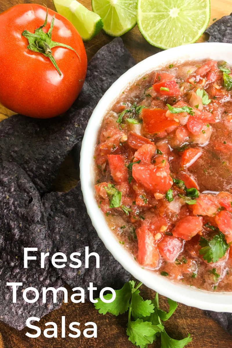fresh tomato salsa in white bowl with blue tortilla chips.