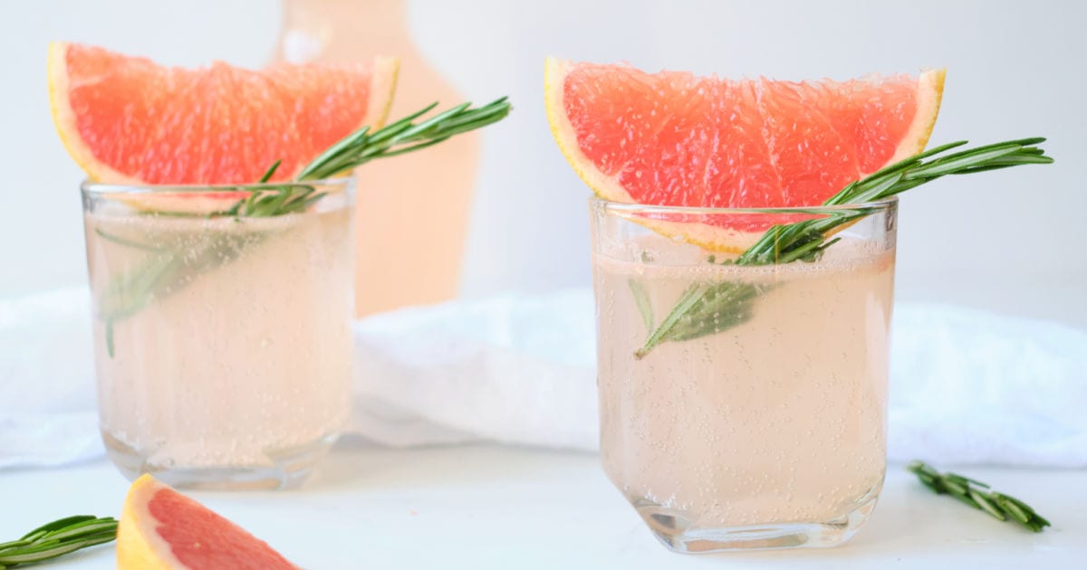 two glasses of sparkling pink grapefruit juice with rosemary.
