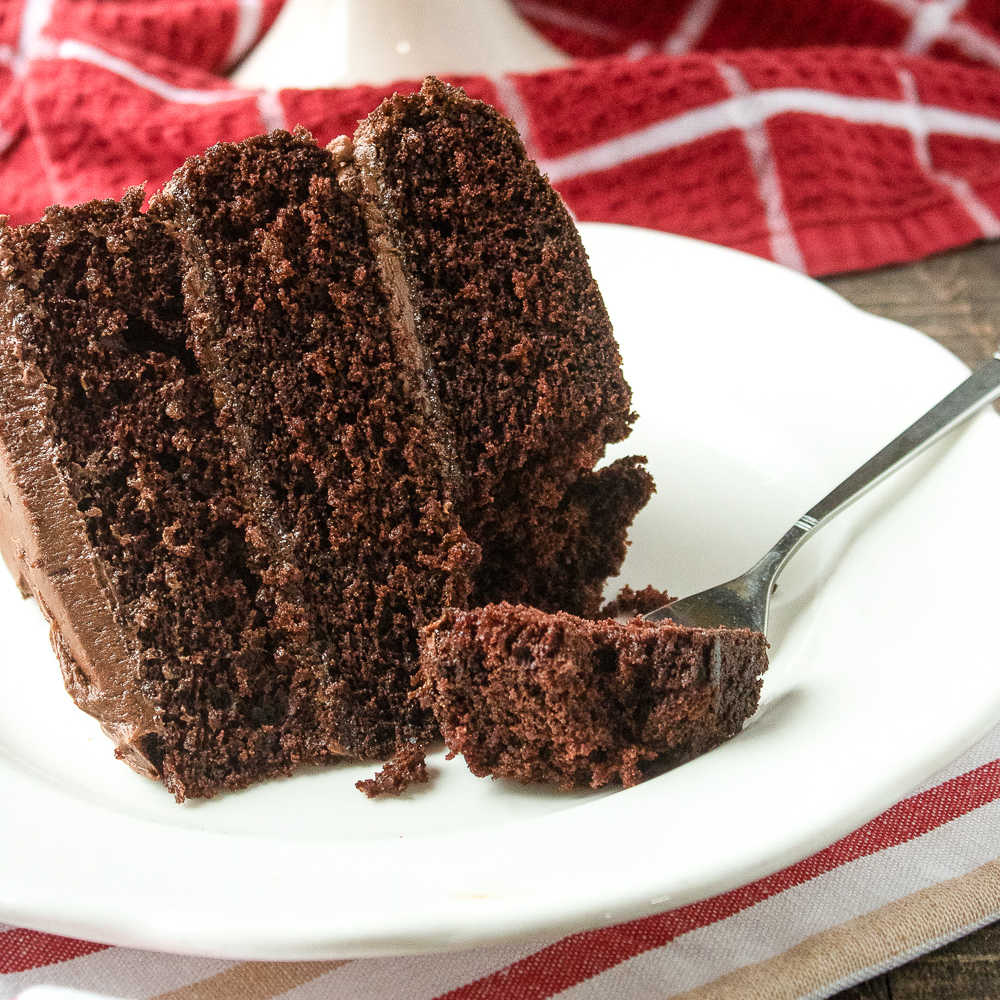 chocolate layer cake on white plate with fork.