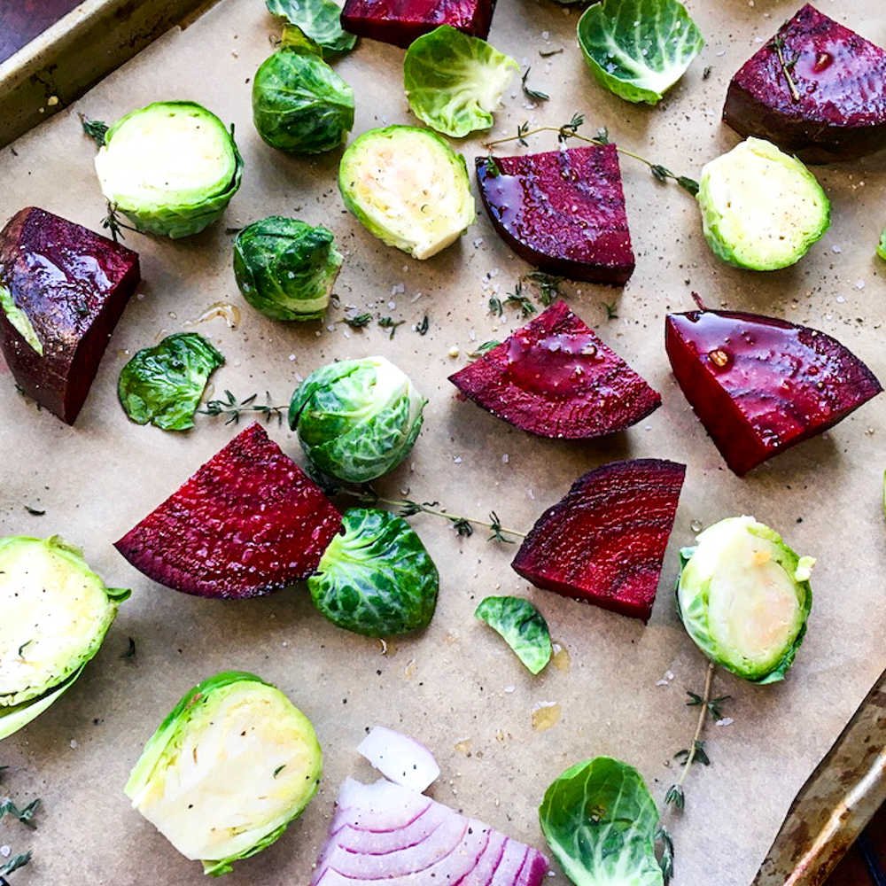 brussels sprouts, beets and red onions on baking sheet.