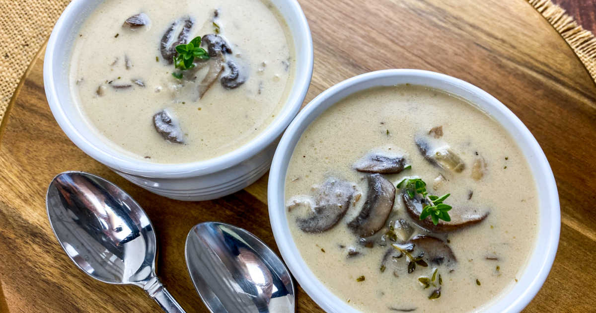 two white bowls of mushroom soup and two spoons.