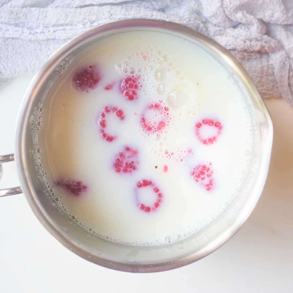 milk and raspberries in pan to make raspberry hot cocoa