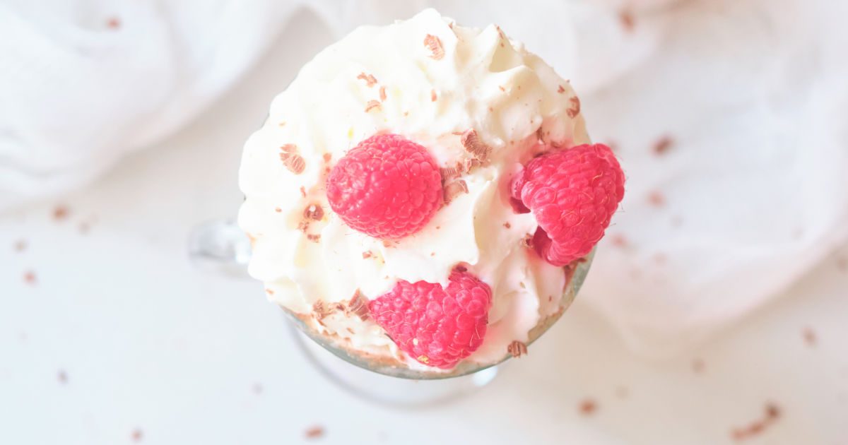 whipped cream and raspberries on top of hot cocoa