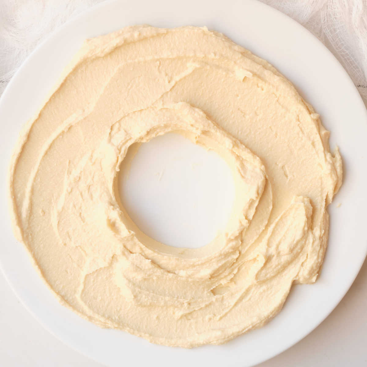 making hummus wreath on white plate